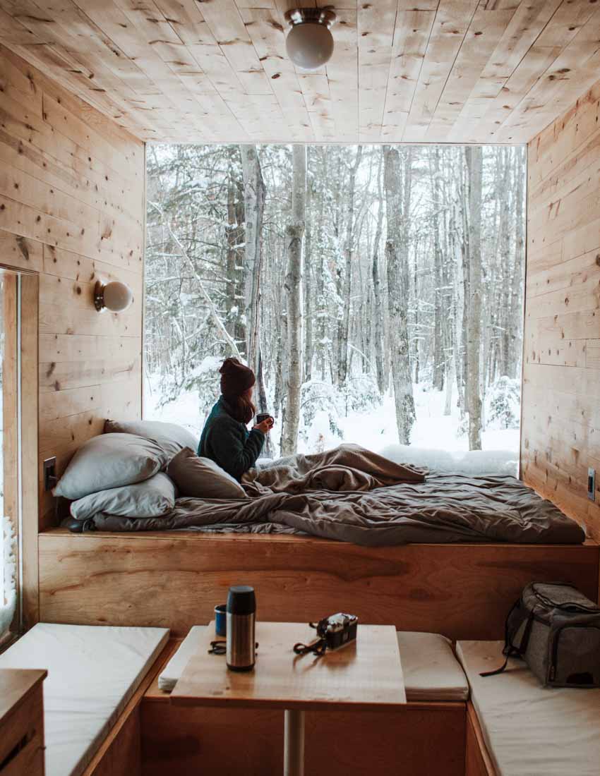 Luxury candle scent image for one of flure's top selling fragrance scents called understated beauti. Picture of a cozy cabin looking out to the white snow outside. Feeling cozy and warm inside.