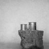  Large and medium sized silver travel tin candle of scent figure wide shot in black and white.