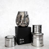 Group image of hand blown glass candle next to tin candles.