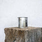 Large sized silver travel tin candle of scent figure wide shot.