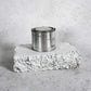 Medium sized silver travel tin candle of scent figure wide shot.