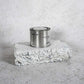 Medium sized silver travel tin candle of fragrance scent sacred wide shot.