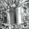 Medium sized silver travel tin candle of fragrance scent toscana - close up on metallic background.