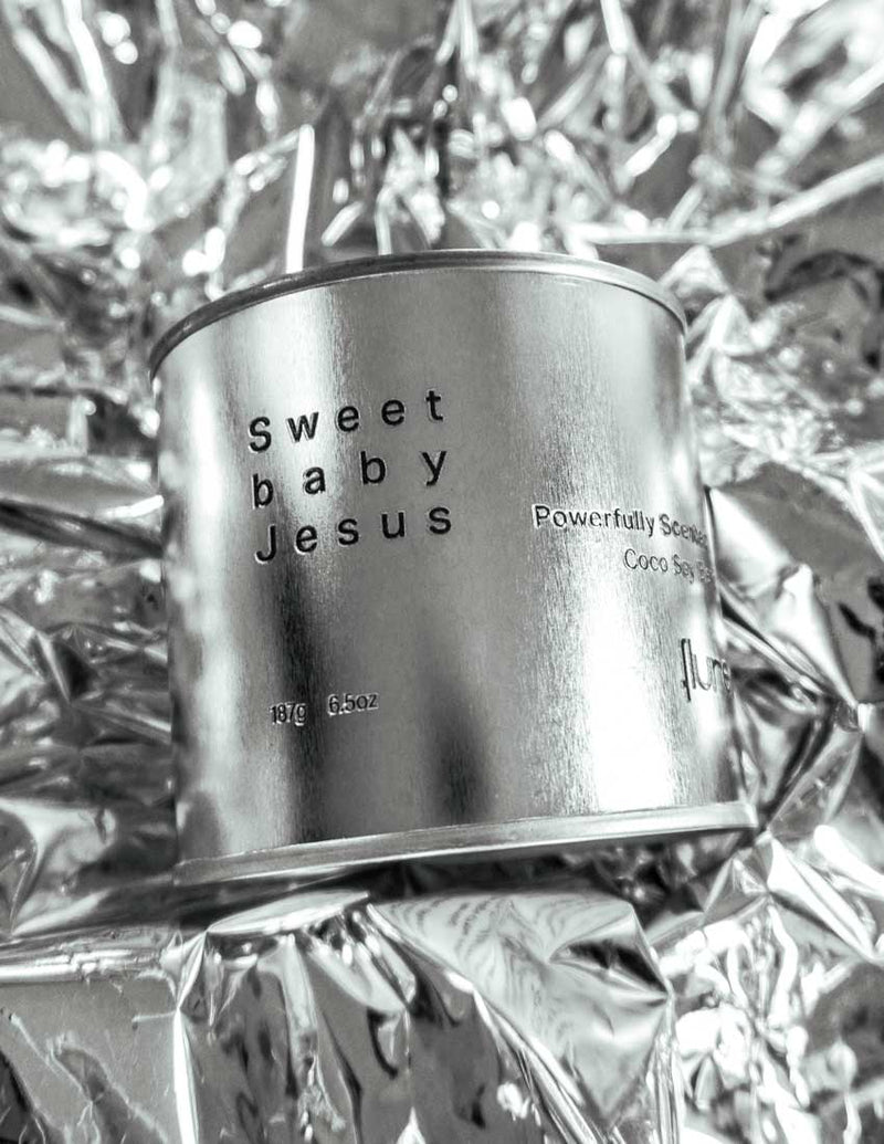 Large sized silver travel tin candle of fragrance scent  sweet baby jesus - close up image on metallic background.