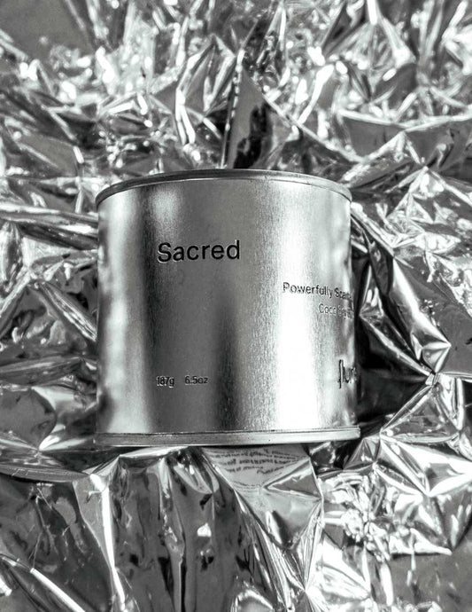 Large size silver travel tin candle of fragrance scent sacred close up on metallic background.