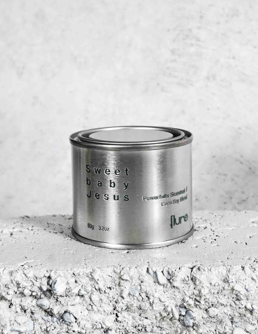 Medium sized silver travel tin candle of fragrance scent sweet baby jesus - close up on brick.