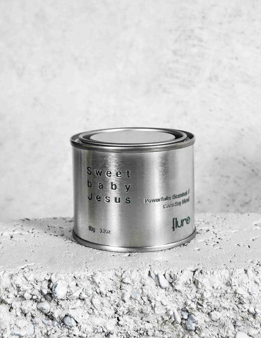 Medium sized silver travel tin candle of fragrance scent sweet baby jesus - close up on brick.