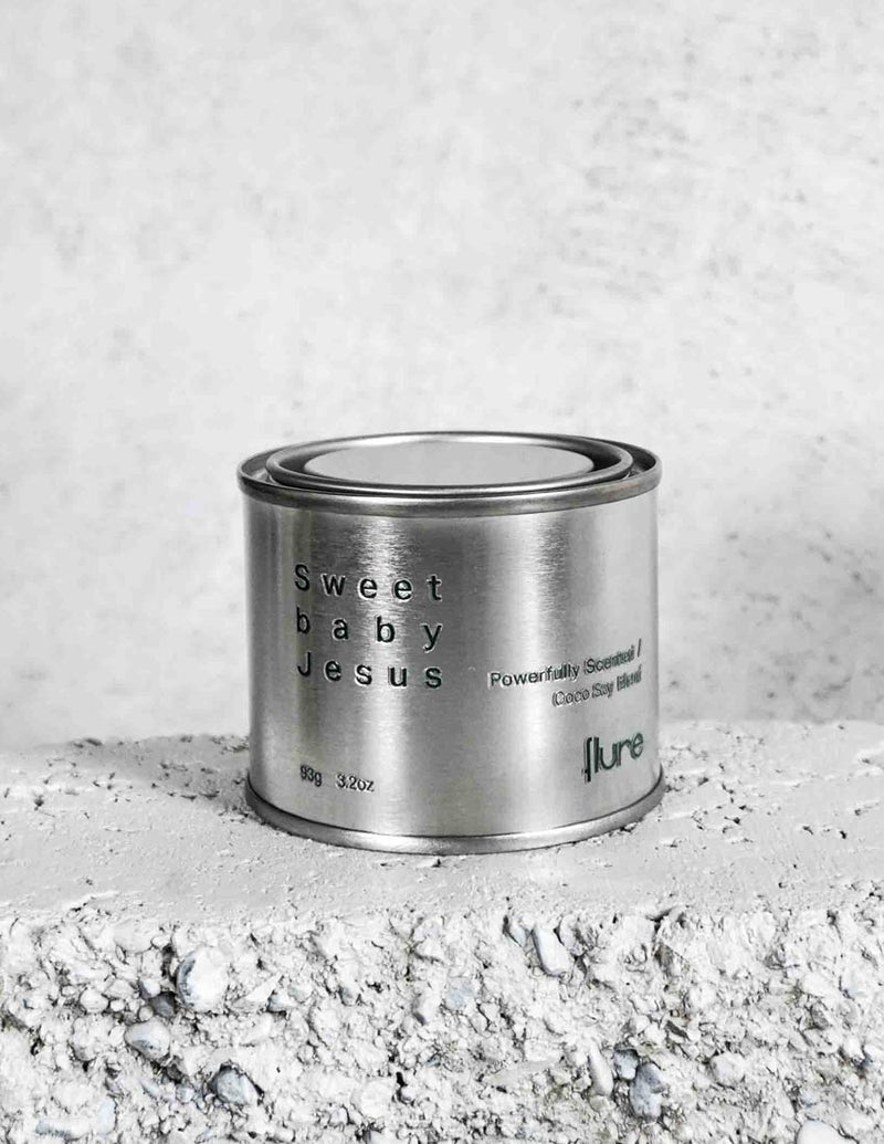 Medium sized silver travel tin candle of fragrance scent sweet baby jesus - close up on brick.