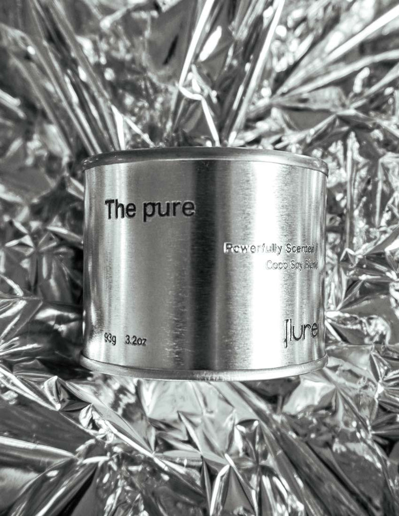 Medium sized silver travel tin candle of fragrance scent the pure - close up on metallic background.
