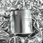 Large sized silver travel tin candle of scent figure on metallic background.