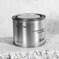 Medium sized silver travel tin candle of fragrance scent spot on, on metallic background - close up  on brick.