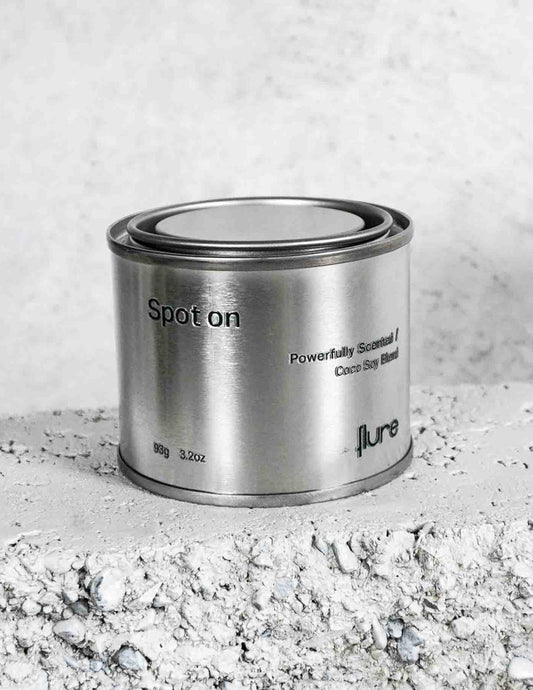 Medium sized silver travel tin candle of fragrance scent spot on, on metallic background - close up  on brick.
