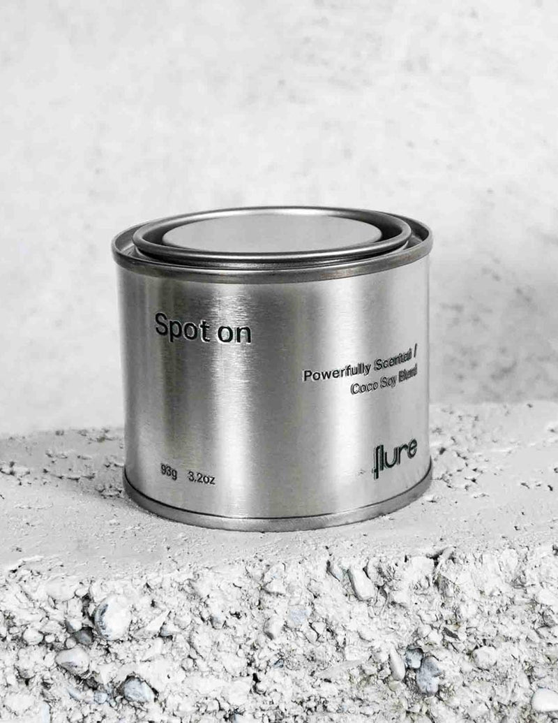 Medium sized silver travel tin candle of fragrance scent spot on, on metallic background - close up  on brick.