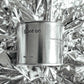 Medium sized silver travel tin candle of fragrance scent spot on, on metallic background - close up.