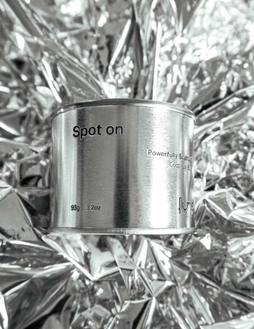 Medium sized silver travel tin candle of fragrance scent spot on, on metallic background - close up.