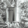 Medium sized silver travel tin candle of fragrance scent spot on, on metallic background - close up.