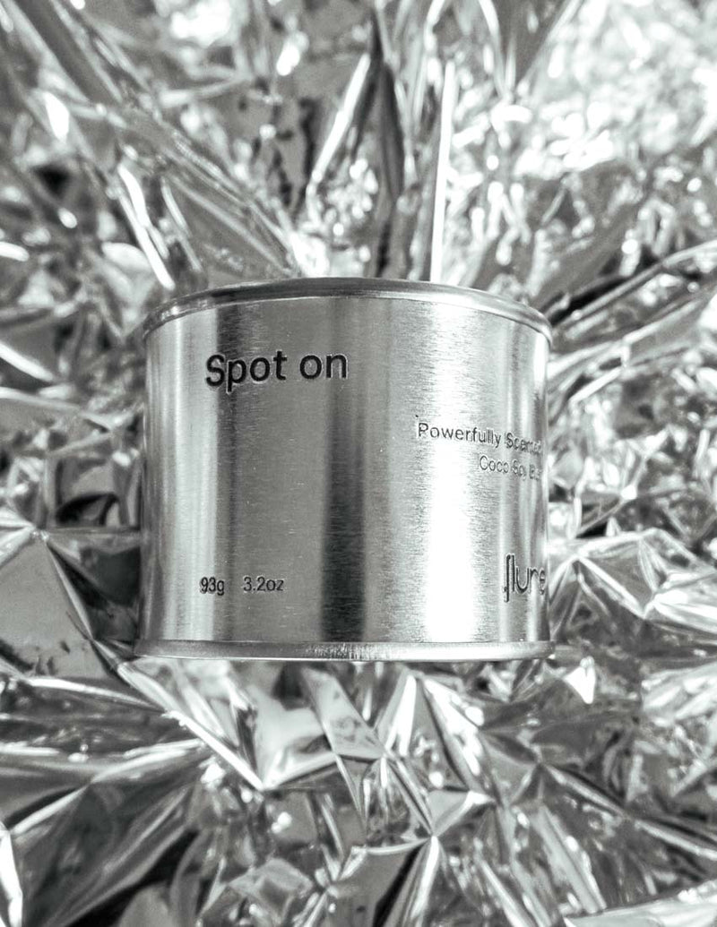Medium sized silver travel tin candle of fragrance scent spot on, on metallic background - close up.