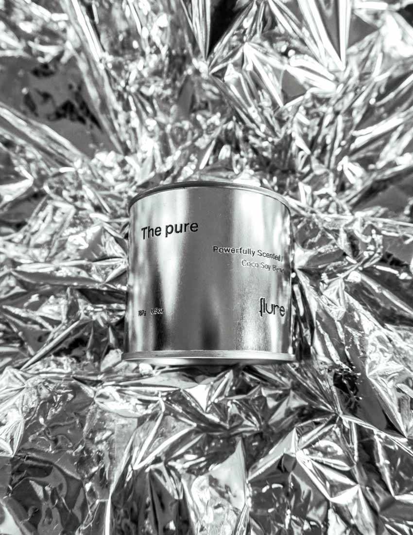 Large sized silver travel tin candle of fragrance scent the pure - close up shot on metallic background.