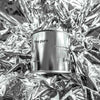 Large sized silver travel tin candle of fragrance scent the pure - close up shot on metallic background.