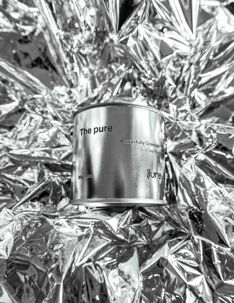 Large sized silver travel tin candle of fragrance scent the pure - close up shot on metallic background.