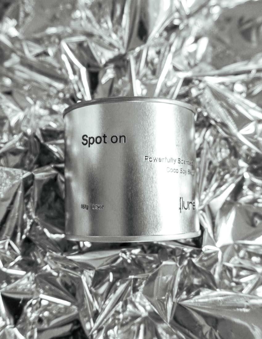 Large sized silver travel tin candle in the fragrance scent spot on  - close up on metallic background.