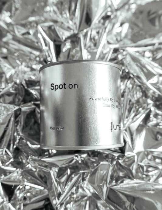 Large sized silver travel tin candle in the fragrance scent spot on  - close up on metallic background.