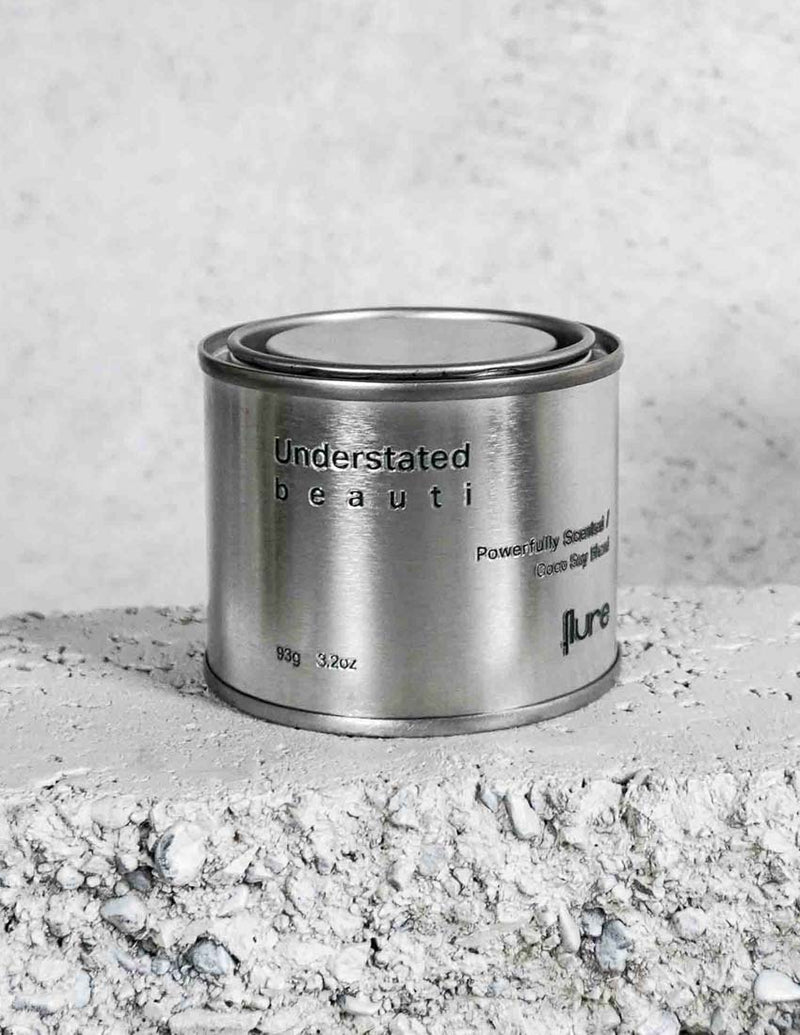 Medium sized silver travel tin candle of fragrance scent understated beauti - close up.